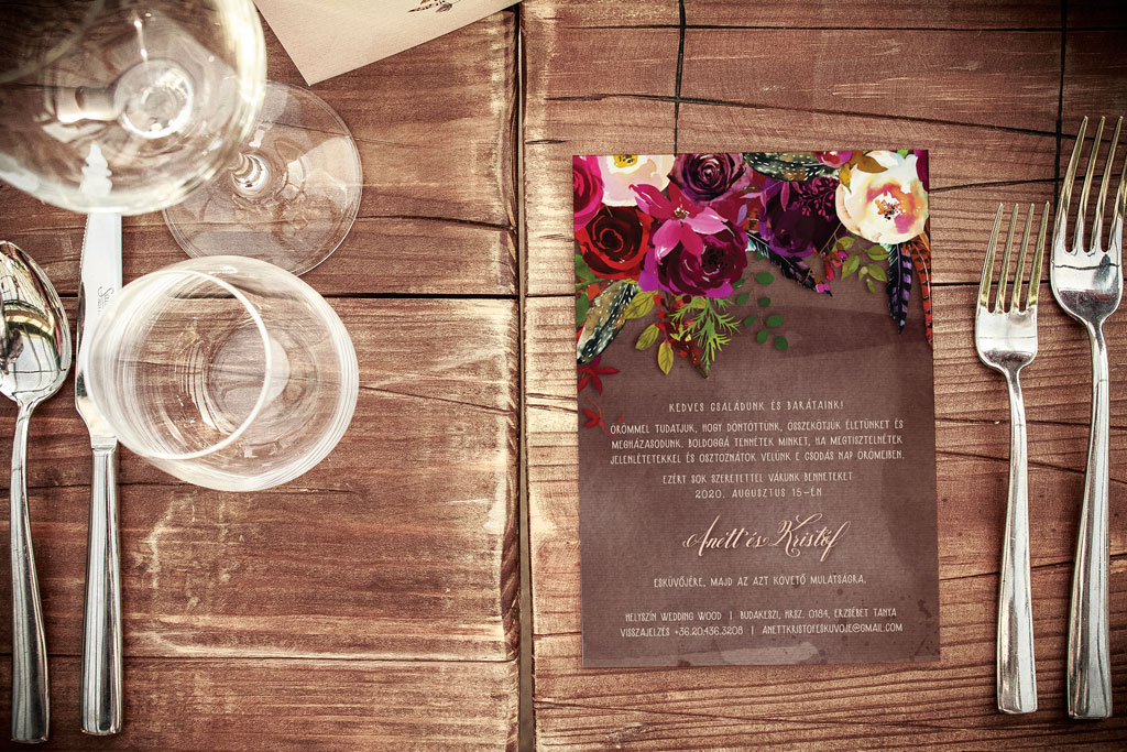 Bohó bordó esküvői meghívó sok színes virággal és változatos levéldíszítéssel, barna vízfestékes alnyomat grafikával és rusztikus hangulatú tipográfiával