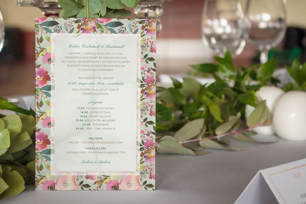 Pink virágos esküvői meghívó élénk és vibráló árnyalatokkal, sok zöld levéllel és halvány zöld alnyomat grafikával, letisztult és modern tipográfiával 