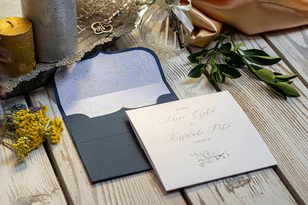 Arany-kék béléses meghívó tusrajzzal készített viágos-leveles mint, arany fóliaprégeléssel nyomva egy ragyogó fehér, textil felületű papírra