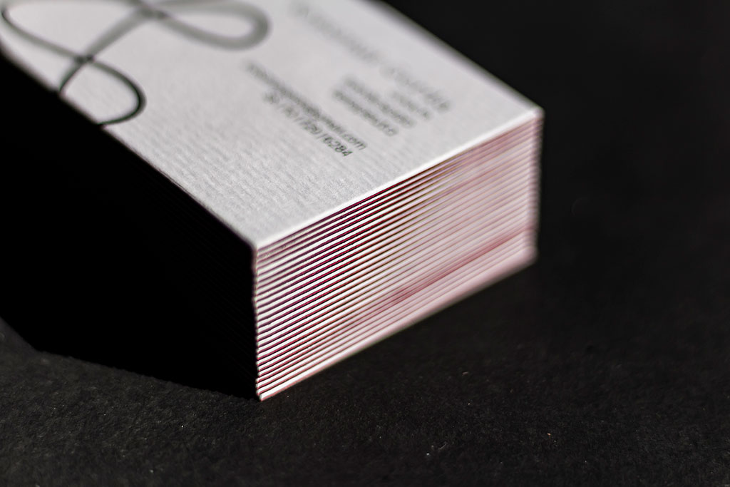 Háromrétegű boltíves névjegy digitfehérrel fekete-fehér-piros színkombinációban, mindkét oldalán nyomtatva 25 féle grafikai motívummal egyedi formára vágva