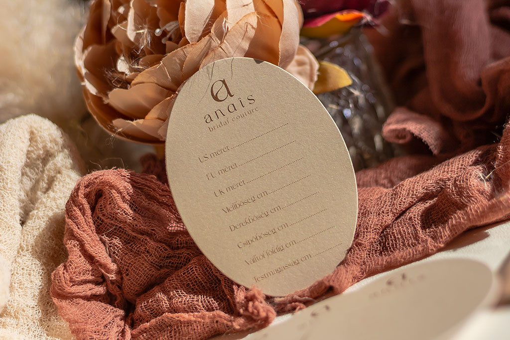 Pezsgőszinű ovális névjegy két rétegben gyöngyházfényű papírból, fehér hátoldallal kasírozva esküvői ruhakészítőknek, opcionálisan kérhető plusz kártyákkal