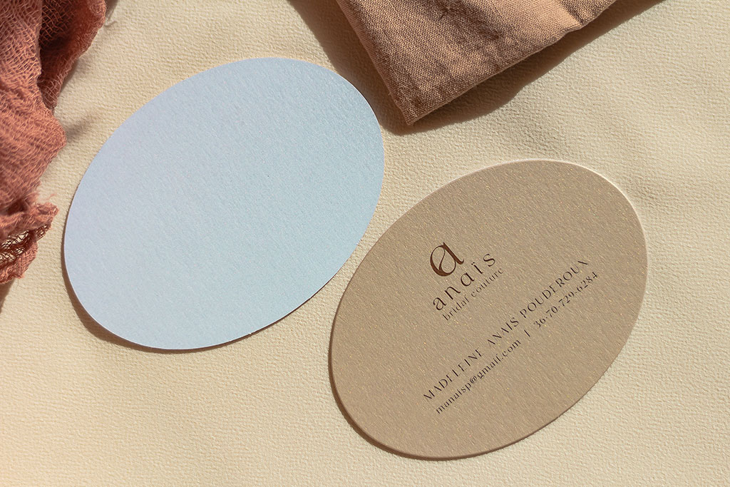 Pezsgőszinű ovális névjegy két rétegben gyöngyházfényű papírból, fehér hátoldallal kasírozva esküvői ruhakészítőknek, opcionálisan kérhető plusz kártyákkal