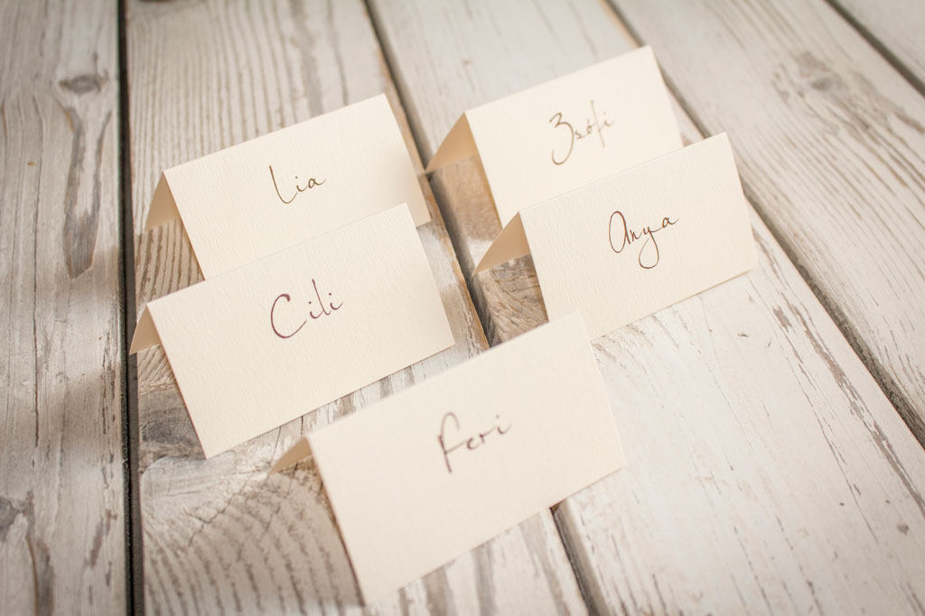 hajtott ültetőkártya kézírásos nevekkel – bármilyen esküvői dekorációhoz sok választható papíron akár aranyozva is, gyors átfutással, kedvező áron