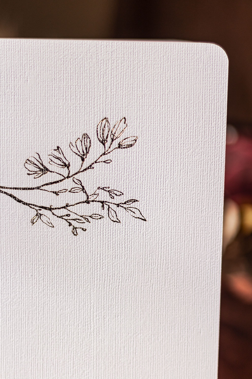 Fehér vászonfelületű füzet arany virággal prégelve: A/5, 64 oldalas, pontozott vonalas, fehér belívvel, sarokkerekített, egyedi paraméterekkel is rendelhető