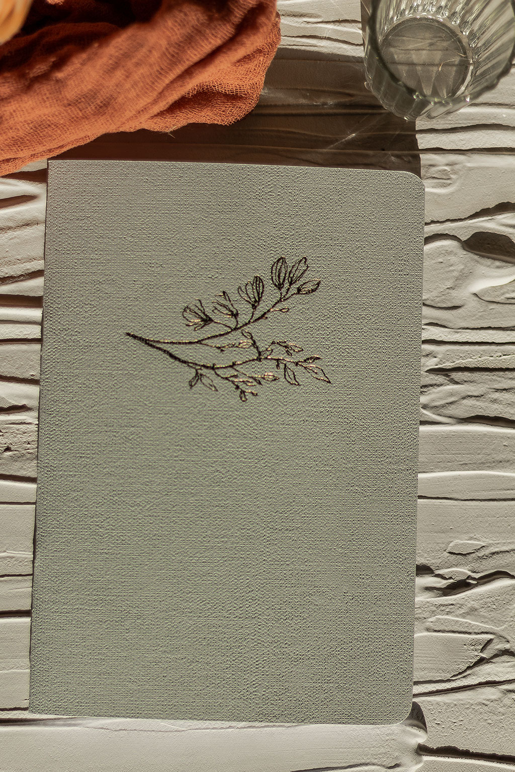 Vászonfelületű kartonból készített füzet arany virággal prégelve: A/5, 64 oldalas, pontozott vonalas, fehér belívvel, sarokkerekített, egyedi paraméterekkel is rendelhető