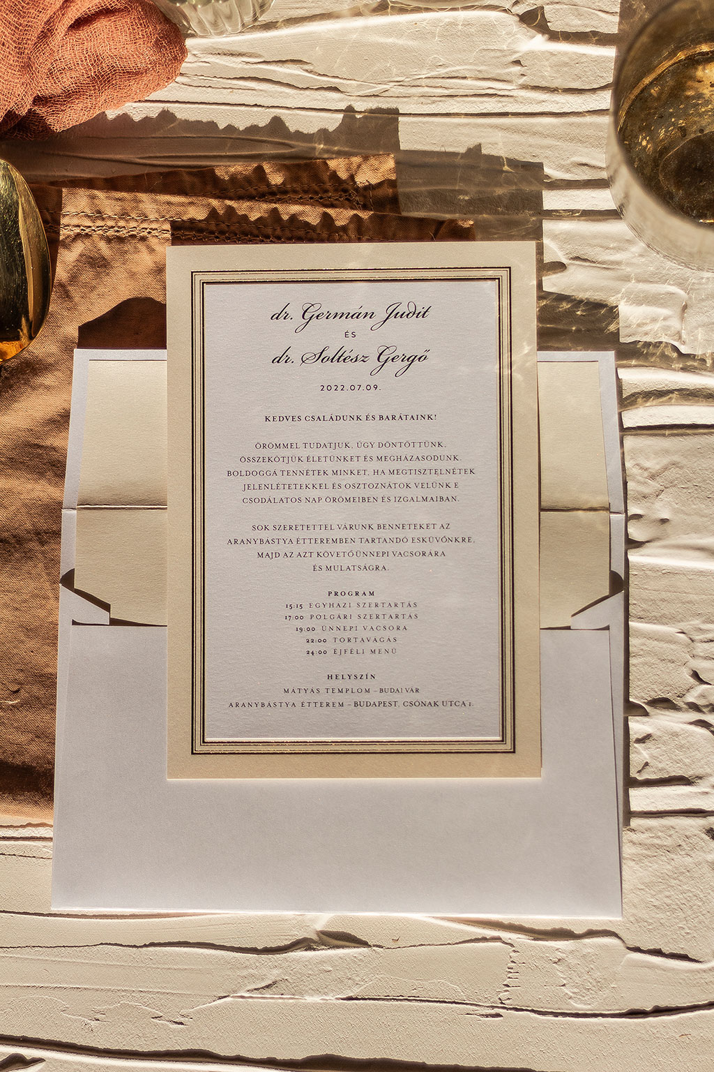 több rétegben ragasztott esküvői meghívó fehér és ekrü színű gyöngyházfényű papírokból, elegáns arany kerettel
