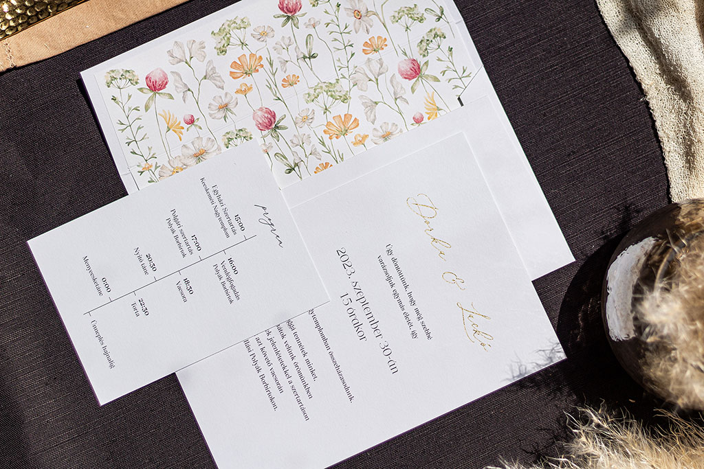 egyedi megrendelésre készített esküvői meghívó szett: aranyozott kártya és boríték, virágos grafikával díszített bélés és egy plusz programkártya